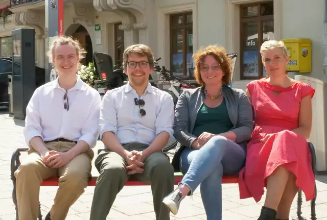 NEOS-Teammitglied Theodor Harnisch, Gemeinderat Bernhard Lutzer, Städträtin Selina Prünster und Gemeinderätin Katharina Fruhmann auf einer Regenbogenbank vor dem Alten Rathaus. | Foto: NEOS/GRÜNE