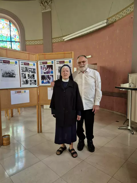 Sr. Maria und der frühere Pfarrer von Herz Jesu P. Hermann Oehm vor einer der Text-und Bildtafeln.