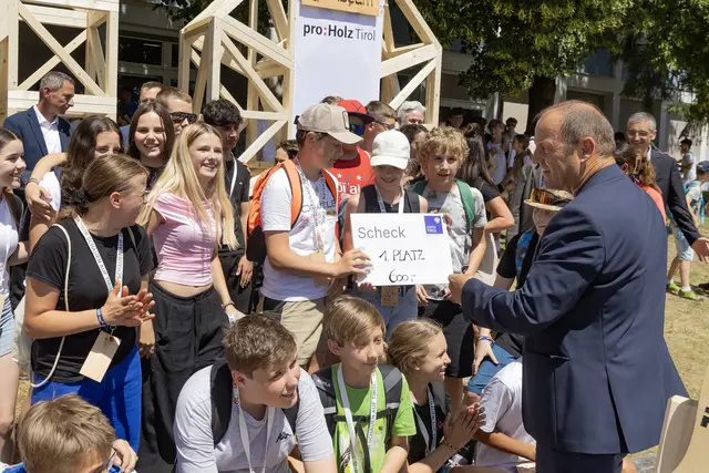 Landeshauptmann-Stellvertreter Josef Geisler übergibt den Scheck an die Schülerinnen und Schüler. | Foto: proHolz Tirol