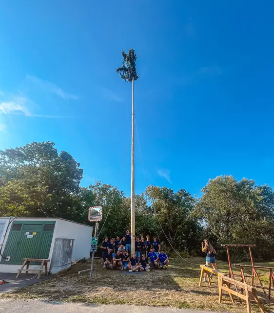Mit dem traditionellen Kirtagsbaumaufstellen durch die Burschenschaft Stöttera wurde der Festauftakt feierlich eingeläutet – und der Baum ragte bald stolz in den blauen Sommerhimmel. Wer zuschaute, hatte schon das erste Getränk in der Hand, denn rund um den Sportplatz war’s schon ordentlich gesellig. | Foto: Burschenschaft Stöttera 