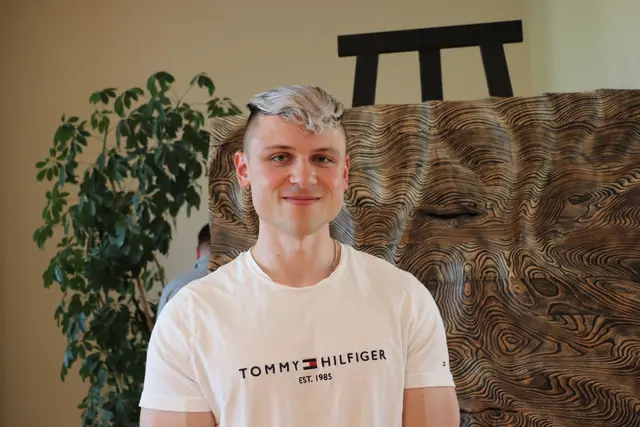 Markus Koren arbeitet als Techniker. Als gelernter Tischler hat er sich der Kunst als Bildhauer mit Holz verschrieben. Die Skulptur "Fluss des Lebens" im Hintergrund entstand aus Eschenholz. Erst mit dem Winkelschleifer bearbeitet, entstand die Struktur nach Sandstrahlen und Lackierung in aufwändiger Handarbeit.  | Foto: Edith Ertl