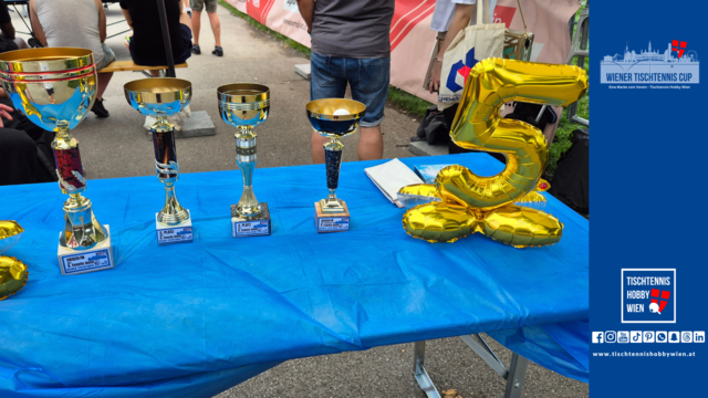 Die glänzenden Trophäen des Tischtennis-Highlights vor sportlichen Hintergrund - daneben ein goldener Luftballon mit der Zahl 5 als Zeichen für 5 Jahre Tischtennis Hobby Wien. | Foto: Tischtennis Hobby Wien