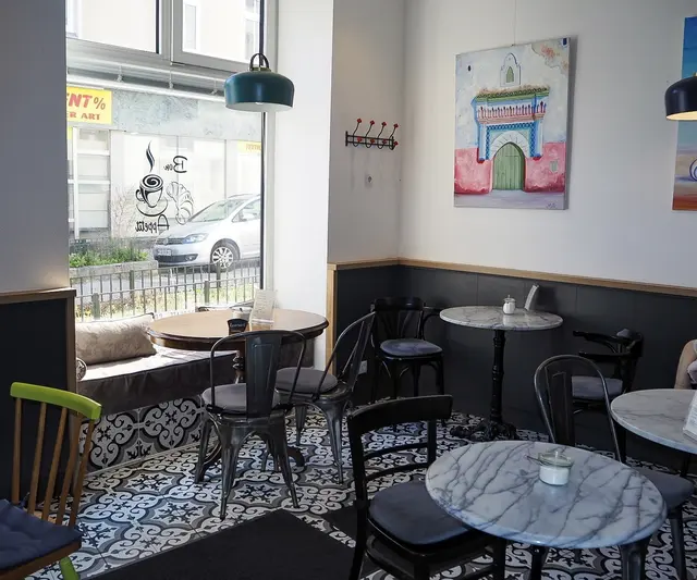 Geschmackvolle Bistrotische verteilen sich im Raum und werden umgeben von kunstvollen Bildern. | Foto: Anna Rauchecker