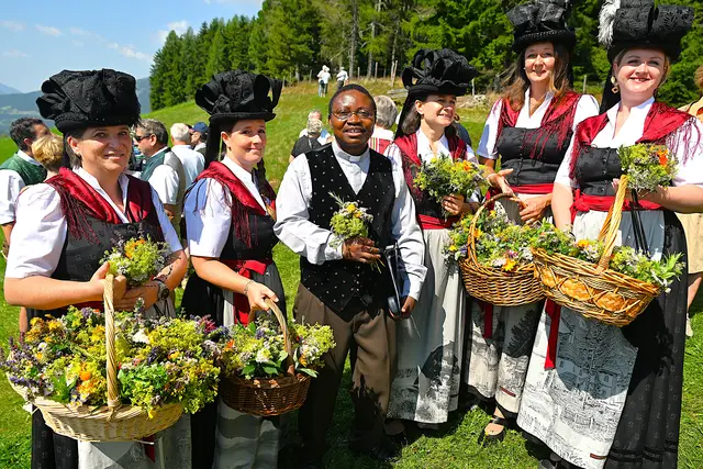 Pfarrer Alexander Chukwujindum Uzoh  mit den Bänderhutfrauen beim Verteilen der Kräutergestecke | Foto: Josef Bodner