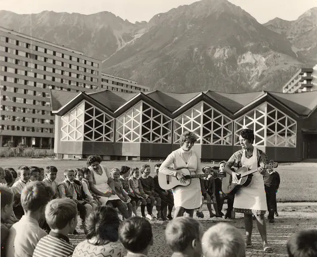 Eine Gruppe des Kindergartens Olympisches Dorf singt für den Fotografen ein Willkommenslied, begleitet von zwei Pädagoginnen auf ihren Gitarren. | Foto: Stadtarchiv Innsbruck