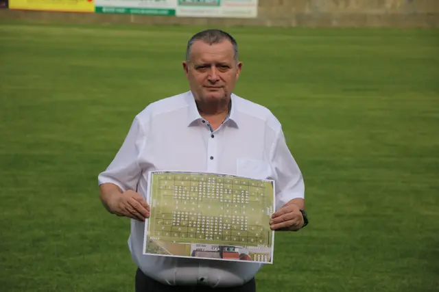 Auf dem neuen Sportplatzrasen in Hadersdorf: Heinrich Becker präsentiert den Lageplan der Rasen-Patenschaften.