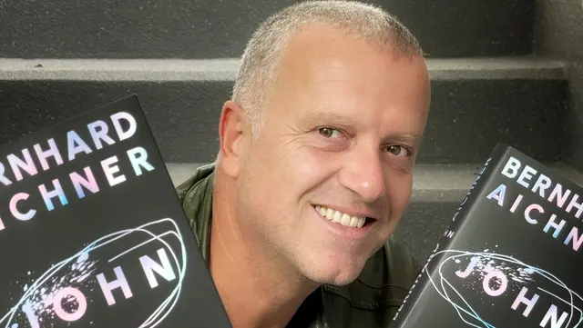 Der österreichische Bestsellerautor Bernhard Aichner mit zwei Exemplaren seines Buches „John“. | Foto: fotowerk.at