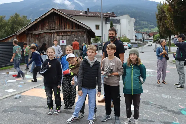 Johannes Schönherr, der Obmann des Klima-, Umwelt- und Agrarausschusses der Stadt Landeck umgeben von Kindern, die im Zuge des autofreien Tages die Römerstraße in Perjen bemalten.  | Foto: Elisabeth Zangerl