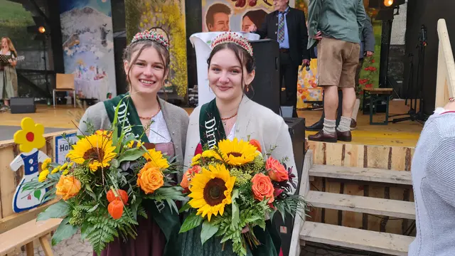 Die frisch gekrönte Dirndlkönigin und ihre Prinzessin strahlen nach der feierlichen Übergabe am Dirndlkirtag mit ihren prächtigen Blumensträußen in die Kamera. | Foto: Cornelia Strobl
