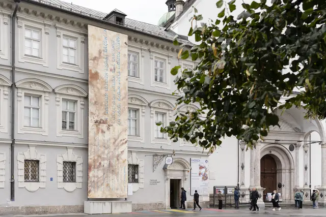 Bis 16.11.2025 ist die mit dem jüdischen Gebet Kaddisch bemalte Leinwand an der Fassade des Tiroler Volkskunstmuseums zu sehen, gestaltet von den Künstlern Oskar Stocker und Luis Rivera. | Foto: Martin Vandory