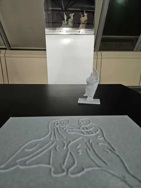 Kunstwerke des taubblinden Künstlers Peter Dimmel

Im Hintergrund ist ein Schaukasten mit zwei Skulpturen des taubblinden Künstlers Peter Dimmel zu sehen. Davor steht ein 3D gedrucktes Modell einer der Figuren, davor liegt eine Platte mit einer 3D gedruckten Zeichnung der zweiten Skulptur.