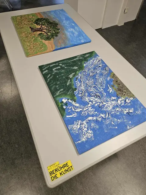 Kunstwerke von Anita Schachinger

Zwei Bilder der taubblinden Künstlerin Anita Schachinger. Das hintere Bild zeigt einen Olivenbaum, das vordere eine Landschaft. Beide Bilder wurden mittels Einsatz von Strukturmasse erstellt und haben deswegen erhabene Strukturen, die man ertasten kann. Am Tisch ist eine 3D gedruckte Plakette in gelb, auf der in schwarzer Schrift und Braille sthet "Berühre die Kunst"