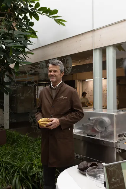 Im Betrieb steht auch ein Kakaobaum – Hubert Berger hält hier in seinen Händen eine Kakaofrucht (Attrappe) – der Baum wird nicht bestäubt, daher trägt er auch keine Früchte. | Foto: Confiserie Berger