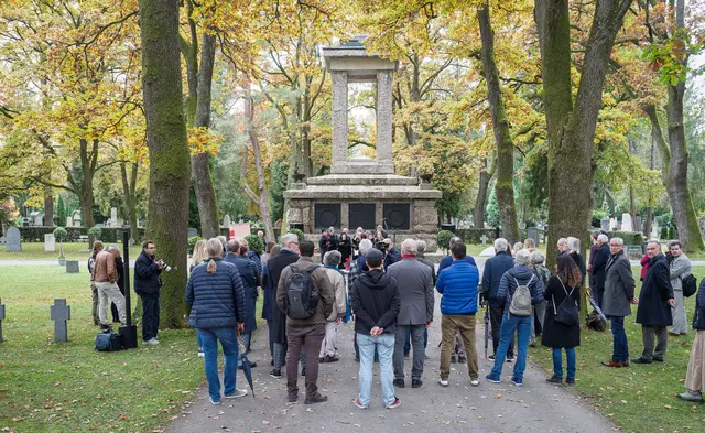 Aus Anlass der Aufstellung des Infopults hat die Stadt Salzburg eine Gedenkstunde im Kommunalfriedhof begangen. Das Denkmal wurde 1929 zur Erinnerung an die gefallenen Soldaten des Ersten Weltkriegs errichtet und nach 1945 um jene des Zweiten Weltkriegs erweitert. Dass damit auch unkommentiert Soldaten miteingeschlossen wurden, die als Wehrmachtsangehörige oder Mitglieder der Waffen-SS an Kriegsverbrechen beteiligt waren, und somit auch diese gemäß dem Text des auf Bronzetafeln eingearbeiteten Gedichts von Anton Pichler als Helden und Vorbilder geehrt werden, sorgte seit den 1980er-Jahren für anhaltende Kritik.  | Foto: Stadt:Salzburg - Alexander Killer