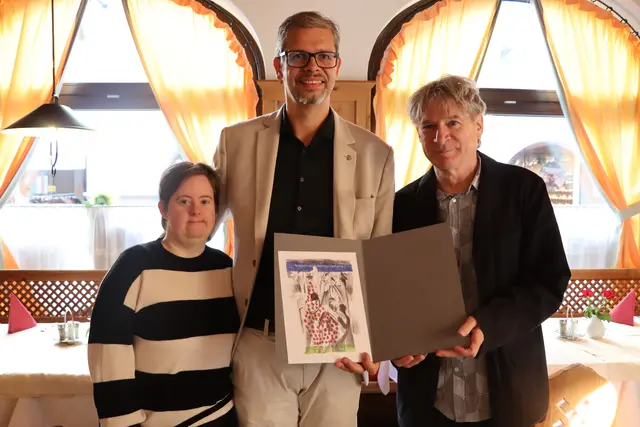 Künstlerin Beatrix Indrist, Rotary Club Lienz-Präsident Bertram Steiner und Künstler Michael Hedwig mit der Neujahrsentschuldigungskarte 2026. | Foto: Lea Mayr
