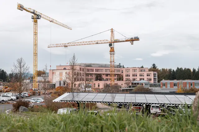 Blick auf das Klinikum Freistadt, davor die neue Parkplatzüberdachung mit PV-Anlage, daneben Baukräne – die Bauarbeiten für den Zubau am Klinikum Freistadt um insgesamt 43,2 Millionen Euro liegen voll im Zeitplan. | Foto: OÖG