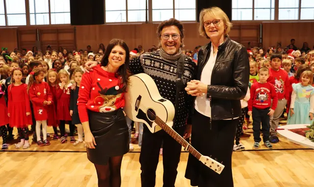 Julia Prünster, Peter Karpf und VS-Dir. Andrea Wagner mit dem größten Volksschulchor Österreichs, der für Licht ins Dunkel "Weihnachten daham" sang. Danke den Eltern, die ihre Kinder schon im Hinblick auf die ORF-Ausstrahlung zu Weihnachten ganz adventlich in die Schule schickten.  | Foto: Edith Ertl