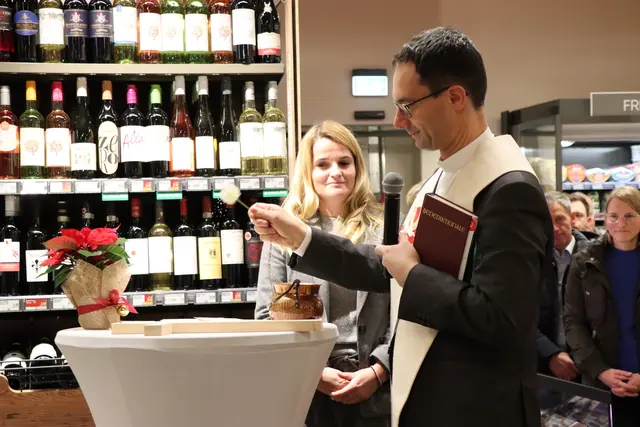 Pfarrer Paul Rauchenschwandtner segnet das Kreuz, das künftig in der Niederauer Spar-Filiale hängen wird. | Foto: Christiane Nimpf