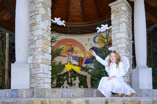 Einladung zur Eröffnung der Kripperlroas in Waldneukirchen. Engelchen Sophia freut sich über die Krippe in der Waldkapelle