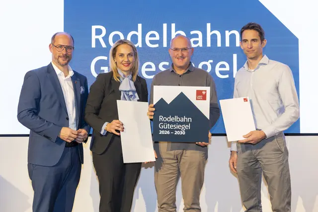 Landesrat Mario Gerber (links) gemeinsam mit Reinhard Klier, Sprecher der Tiroler Seilbahnwirtschaft (rechts), und Simone Larcher, Vorständin der Abteilung Sport des Landes Tirol (zweite von links), bei der Verleihung an die Naturrodelbahn Pleisenhütte Axams. | Foto: WKT/Die Fotografen