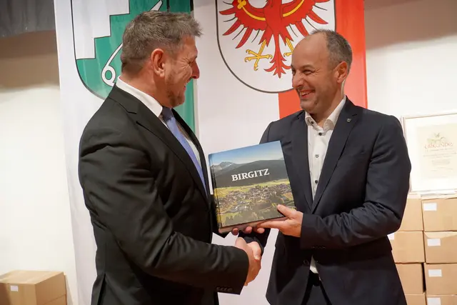 Hans Singer übergab Bürgermeister Markus Haid feierlich das erste Birgitzer Dorfbuch.  | Foto: AMG