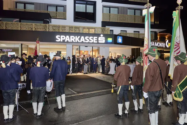 Die modernisierte Filiale der Sparkasse Imst erstrahlt inmitten von Ischgl im neuen Glanz. Bei der Eröffnungsfeier machten auch die Schützenkompanie (r.) sowie die Musikkapelle (li.) ihre Aufwartung. | Foto: Christoph Noesig PHOTOGRAPHY