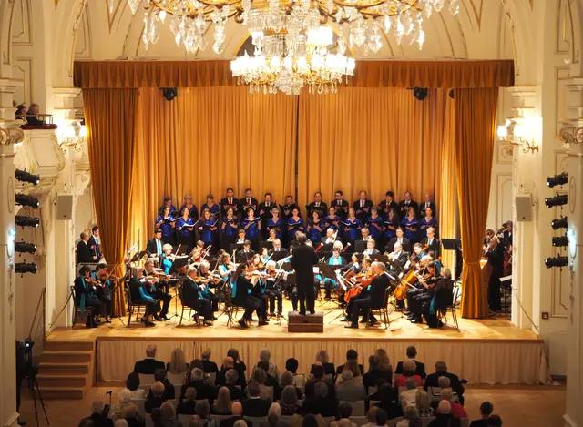 Konzertaufstellung nach der Pause mit dem Sinfonischen Orchester MERKUR, dahinter das Damenvokalensemble Indigo &amp; Herrenvokalensemble Cantores.