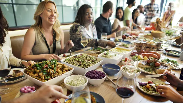 Größere Gruppe an Menschen genießt diverse Speisen in einem Restaurant (Symbolfoto). | Foto: smarterpix/Rawpixel