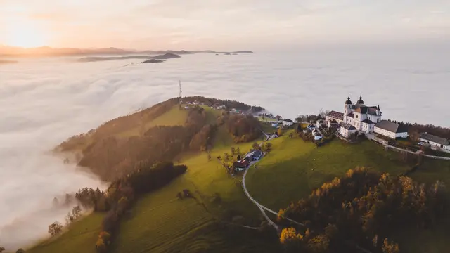 In der sanften Hügellandschaft des Mostviertels breitet sich ein Meer aus Nebel aus, während die warmen Farben des Herbstes die Landschaft in ein malerisches Licht tauchen. Die majestätische Architektur der Klosteranlage thront über den Wolken und lädt zu einem unvergesslichen Besuch ein. | Foto: Niederösterreich Werbung/Sabine Wieser
