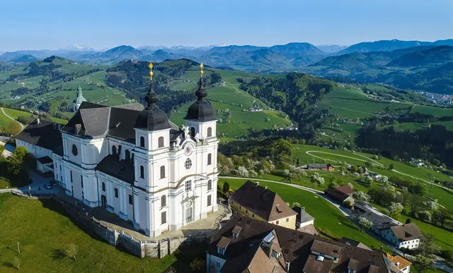 Die Basilika Sonntagberg thront majestätisch über der blühenden Landschaft, umgeben von sanften Hügeln und blühenden Birnbäumen. Im Frühling erstrahlt die Umgebung in einem Meer aus Farben, während die frische Luft die Sinne belebt und zu Erkundungen einlädt. | Foto: Cleanhill Studios, Gerald Prüller