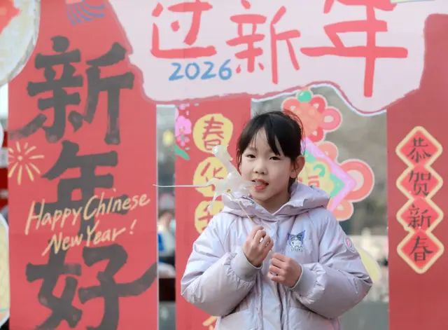 Ein Kind kostet am 4. Februar 2026 auf einem Markt mit Waren zum chinesischen Neujahr in der Stadt Yangzhou in der ostchinesischen Provinz Jiangsu eine Sirup-Figur. | Foto: APA-Images / Eyevine / Meng Delong Xinhua