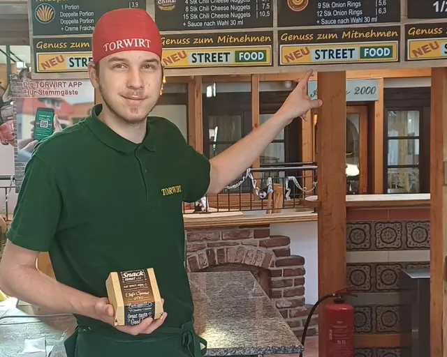 Fabrice zeigt auf das neue Angebot der Streetfood Küche im Torwirt | Foto: Torwirt Wolfsberg
