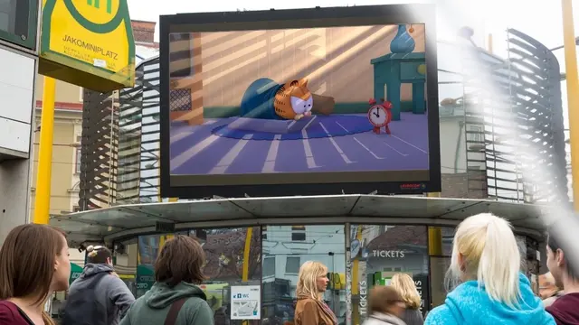 Der montaghassende Comic-Kater Garfield wird demnächst des Öfteren im öffentlichen Raum zu sehen sein. Foto: Garfield-Szene auf einem Infoscreen an der Haltestelle Jakominiplatz in Graz. | Foto: © INFOSCREEN / ©Paws, All rights reserved. “Garfield TV Series” © 2008 Dargaud-Media