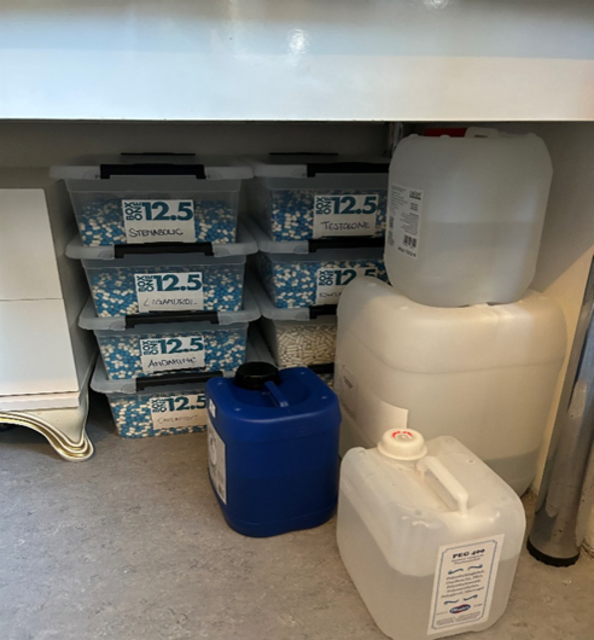 Verbotene Substanzen unter einem Küchentisch in Plastikboxen sowie Kanister mit brennbaren Flüssigsubstanzen. | Foto: Bundeskriminalamt
