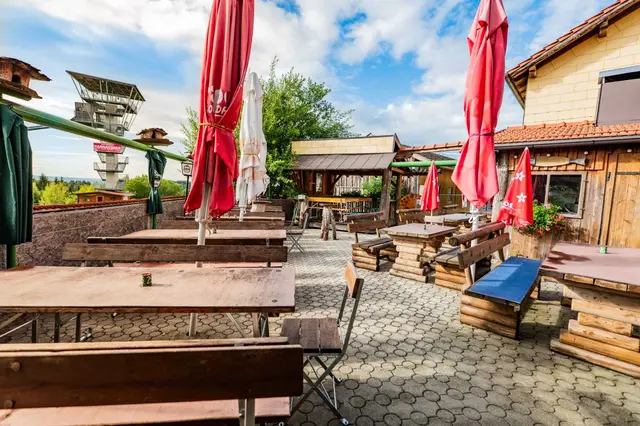 Der gemütliche Gastgarten von Schmiedbauer's Mostschenke mit Blick auf den Skiflyer-Turm. | Foto: MediaDot