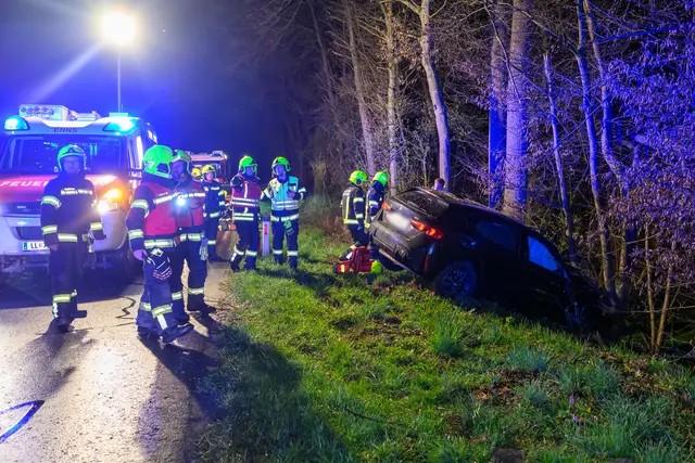 Auto kommt von Straße ab und kracht gegen Bäume am Waldrand