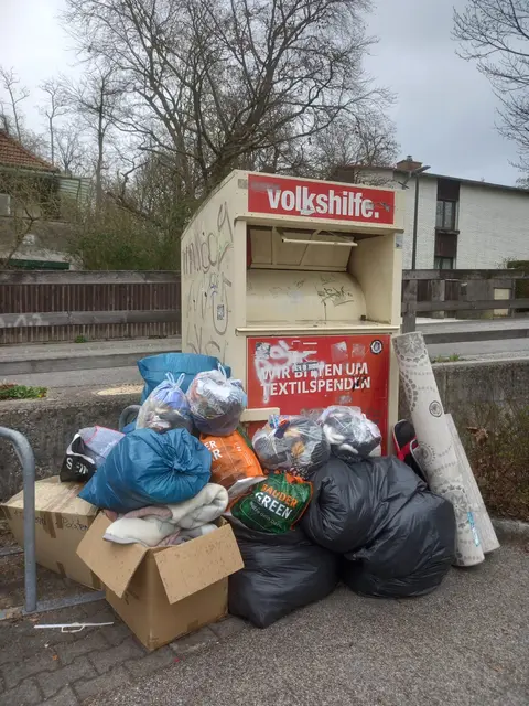 Säcke neben überfülltem Container statt richtig gespendet