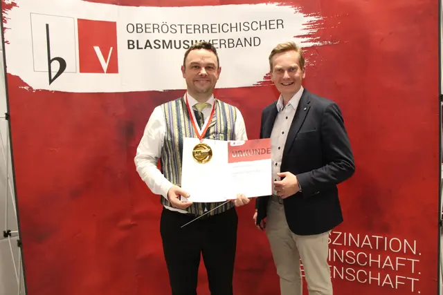 Kapellmeister Arnold Renhardt von der Stadtkapelle Kirchdorf und Bürgermeister Markus Ringhofer freuen sich über die Goldmedaille in der Stufe "E".