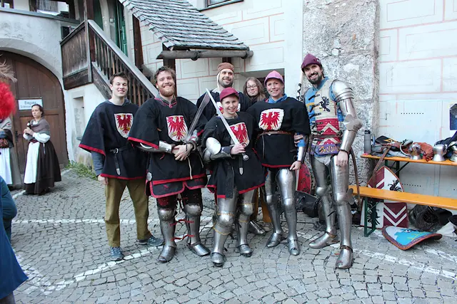 Menschen in Ritterrüstungen vor historischer Altstadt