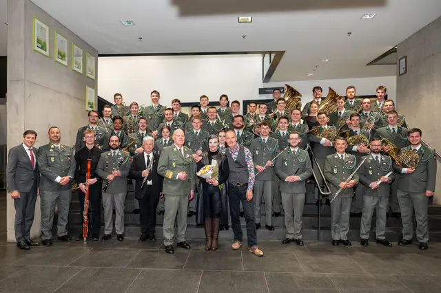 Die Militärmusik Tirol mit LAD Herbert Forster (1. v. l.), Militärkapellmeister Hannes Apfolterer (6. v. l.), Elisabeth de Roo (Mitte) und Dramaturg Andreas Lackner (8. v. l.). | Foto: Land Tirol/Reinhold Sigl