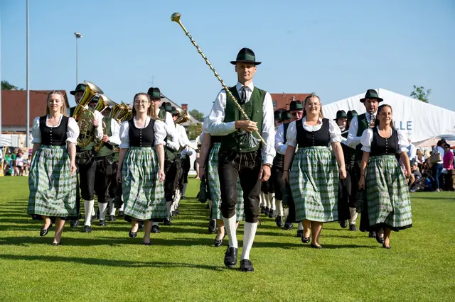 Musikverein Pichl bei Wels in Marschformation in fünf Reihen auf Wiese, ganz vorne sind Stabführer und Marketenderinnen, 