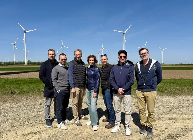 Eine Gruppe Menschen im Freien vor mehreren Windrädern