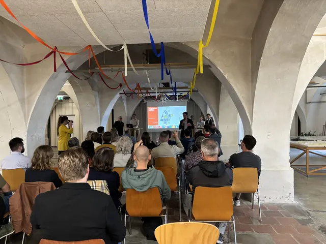 Eine Gruppe von Menschen sitzt und schaut einer Präsentation zu. 
