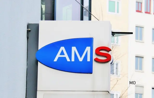 zu sehen ist das AMS-Logo als Schild an einer Hauswand