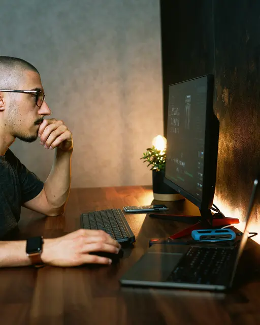Ein Mann sitzt vor seinem Laptop, die Hand auf der Maus.