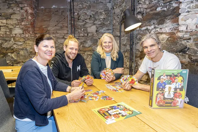 Vier Personen mit Fußballpickerln und dem Panini-Sammelalbum