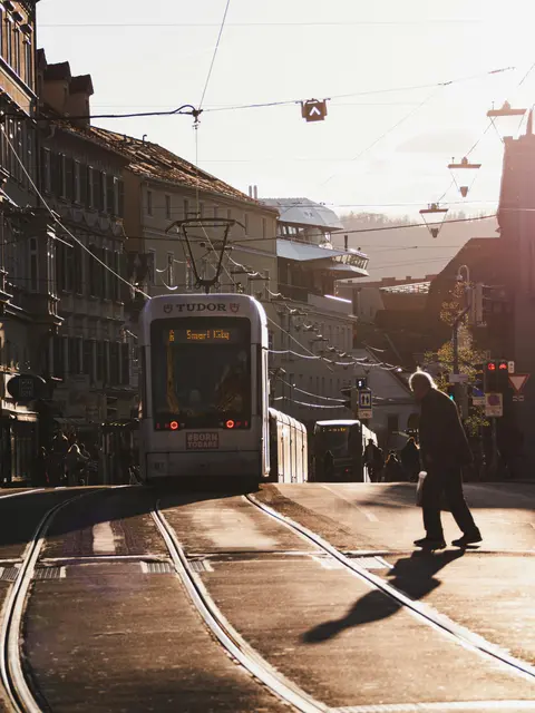Ein Mann überquert die Gleise vor einer Straßenbahn. 