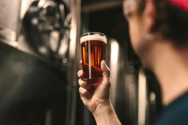 Ein Mann hält ein Bierglas in der Hand.