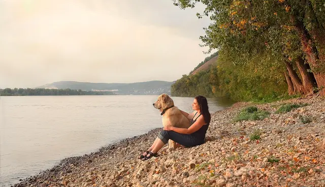 Hund und Frauchen sitzen am Strand