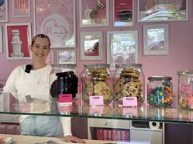 Mimi Prein steht hinter der Vitrine in ihrem Geschäft, darauf Glasbehälter mit Cookies.